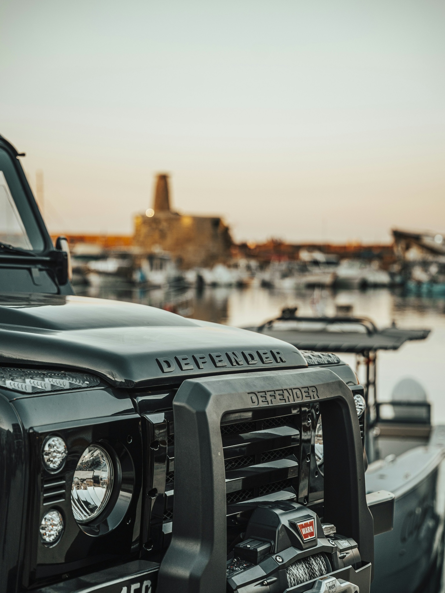 A close-up of a matte green door handle on a custom Branders Land Rover Defender 90 parked outdoors.
