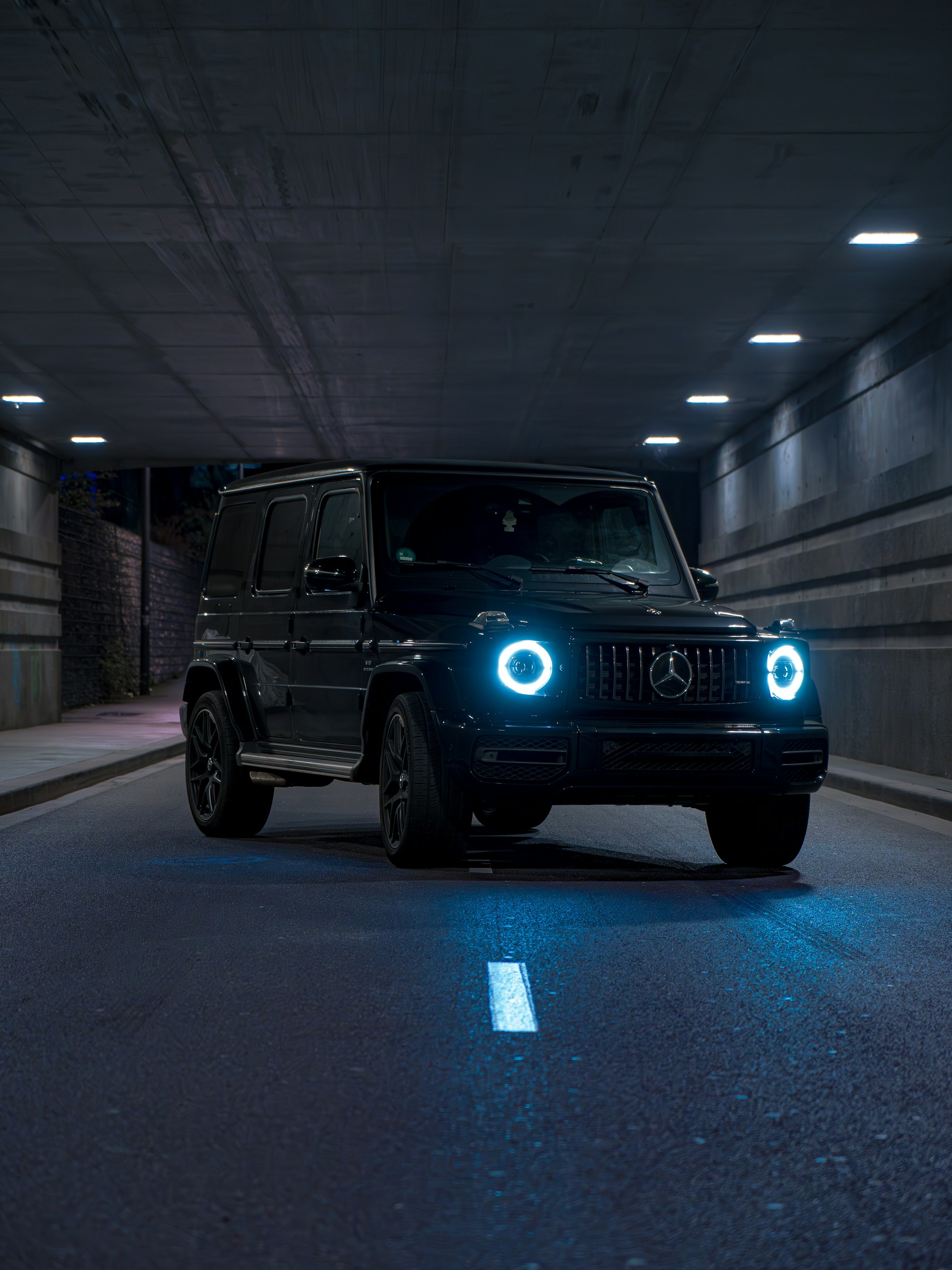 A custom Branders Mercedes G63 with a matte green finish parked on a concrete lot near trees.