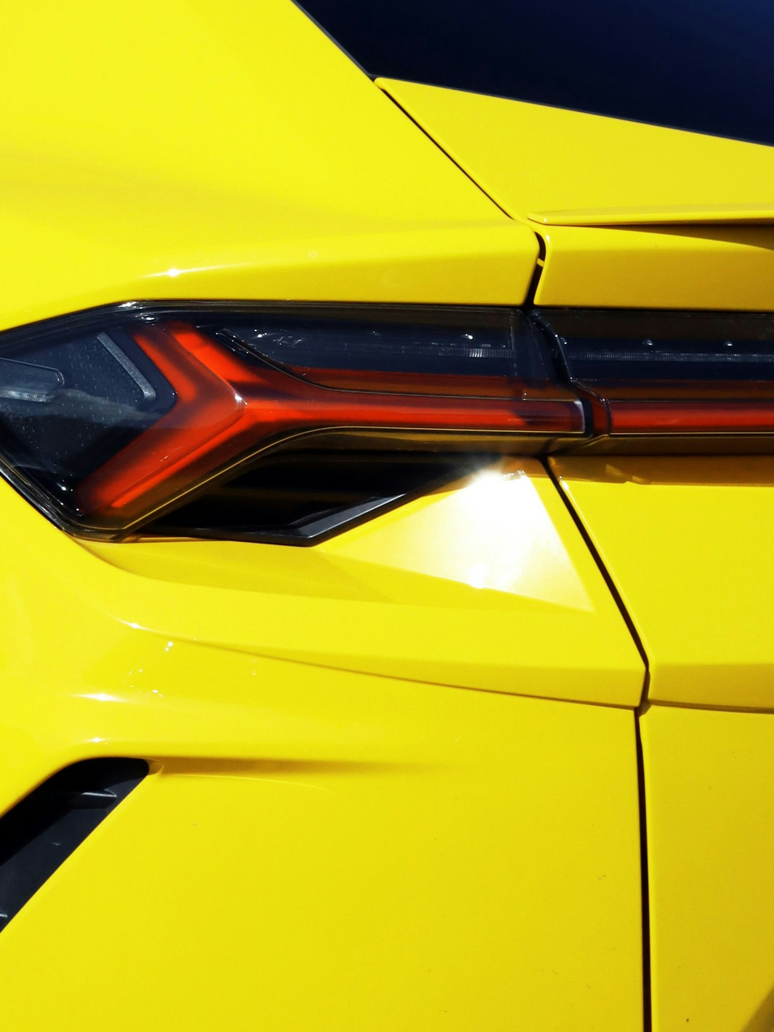 A close-up of the forged carbon fiber rear spoiler on a custom Branders Lamborghini Urus inside a workshop.