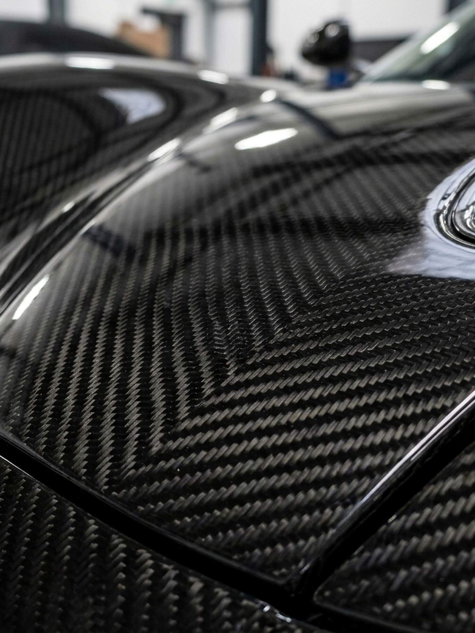 A custom Branders BMW M5 Touring features its open hood revealing a detailed carbon fiber engine bay inside a bright workshop.