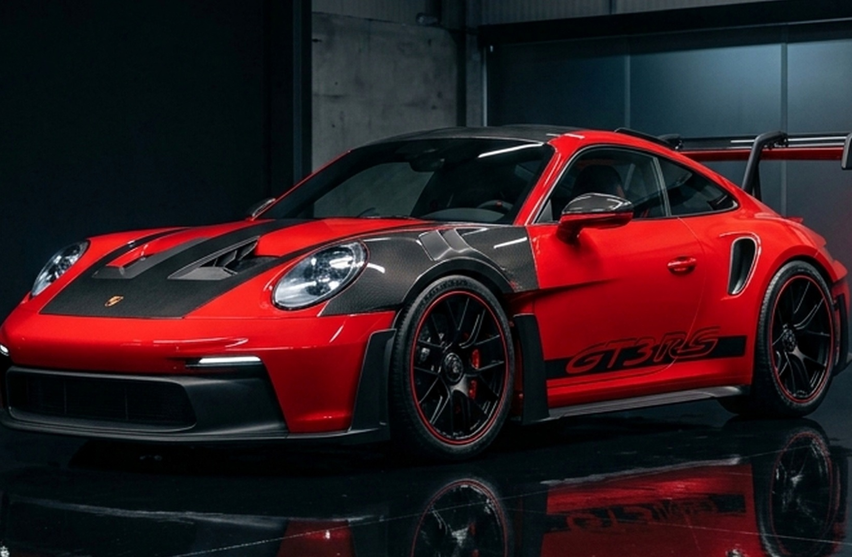 A custom Branders Porsche 911 Carrera Turbo in matte black drives on a wet road under an overcast sky, with trees and streetlights in the background.