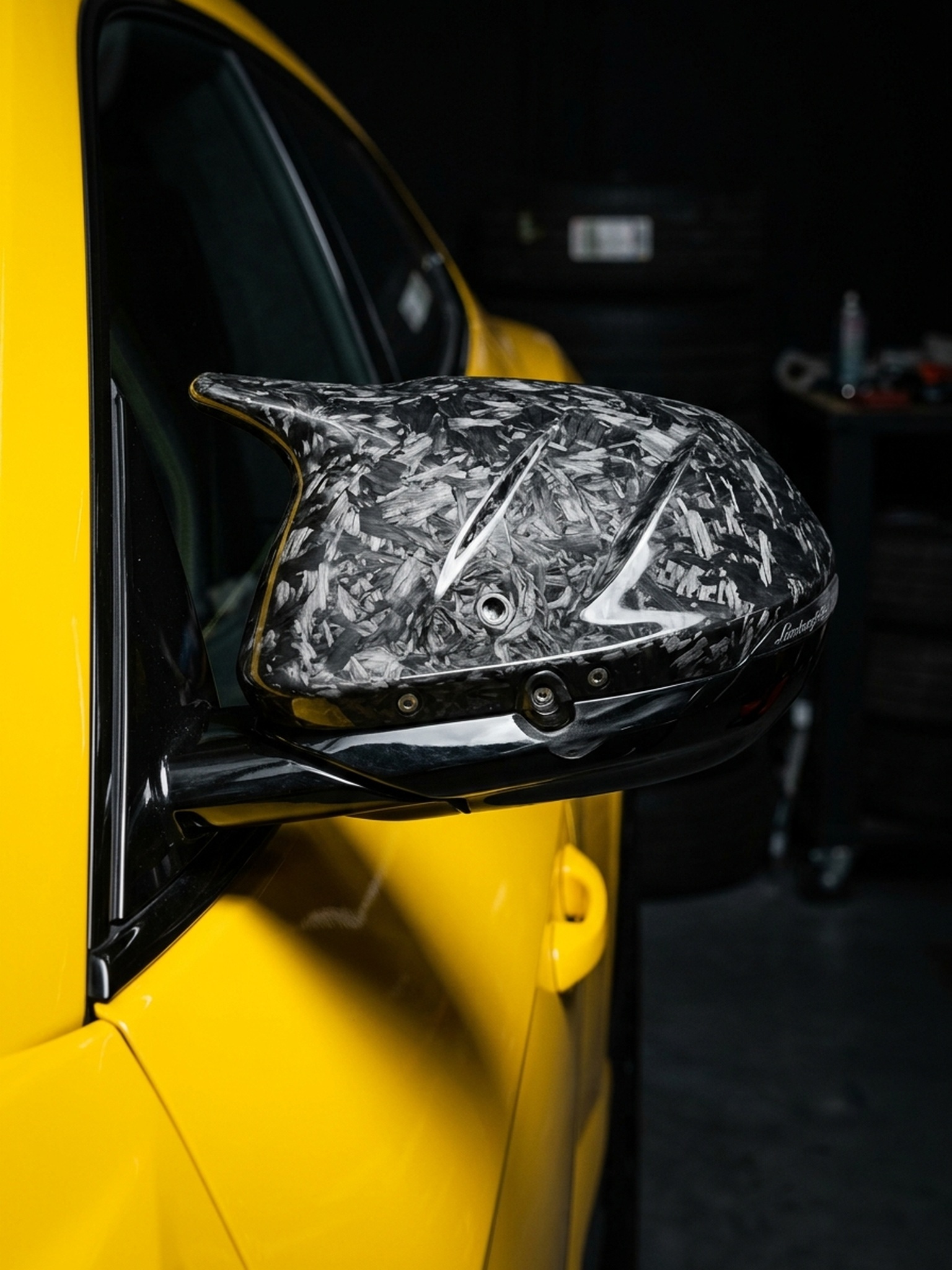 A custom Branders Lamborghini Urus features a forged carbon fiber side mirror cap against its bright yellow bodywork.