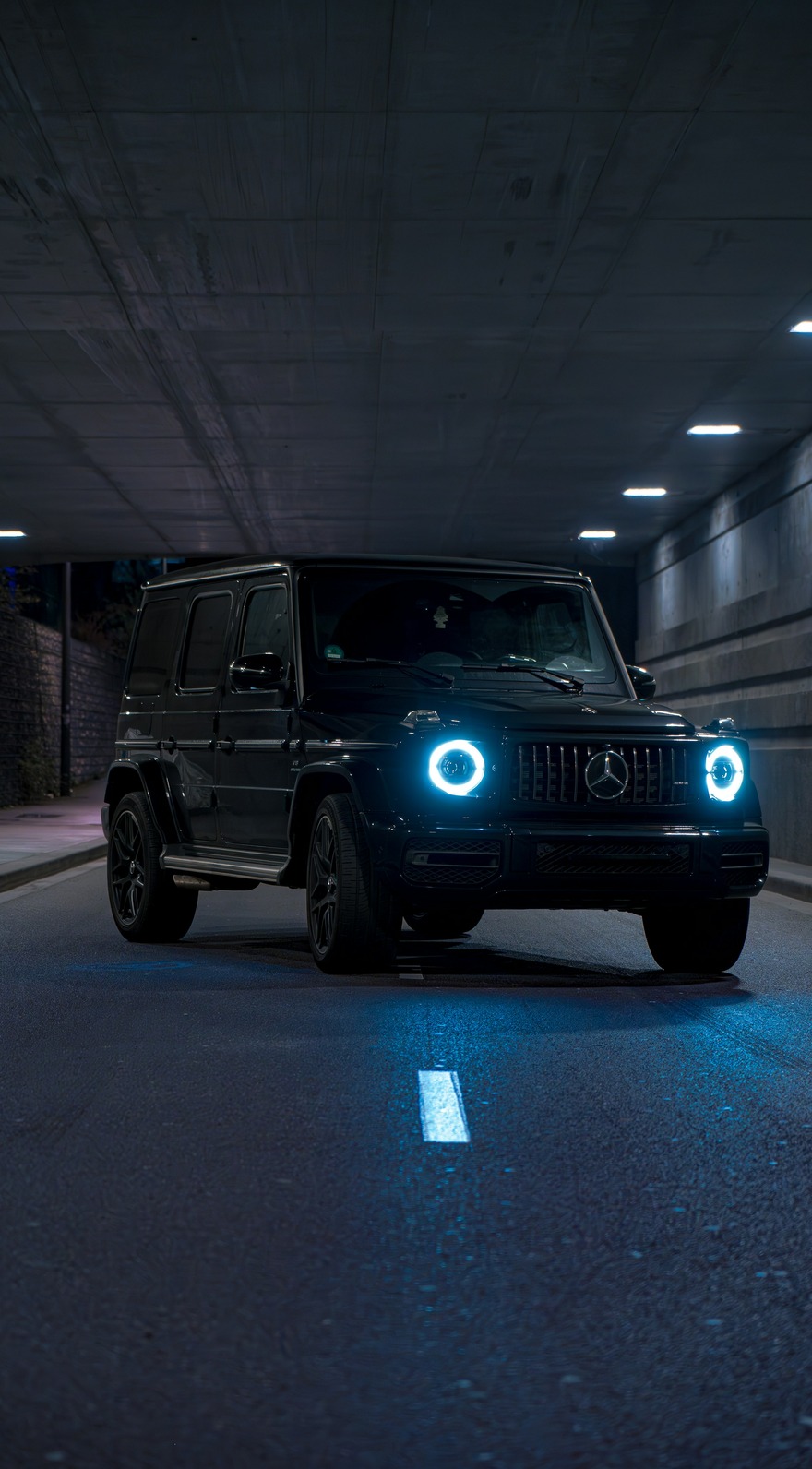 A custom Branders Mercedes G63 covered in mud drives over an earthy hill beneath an overcast sky.